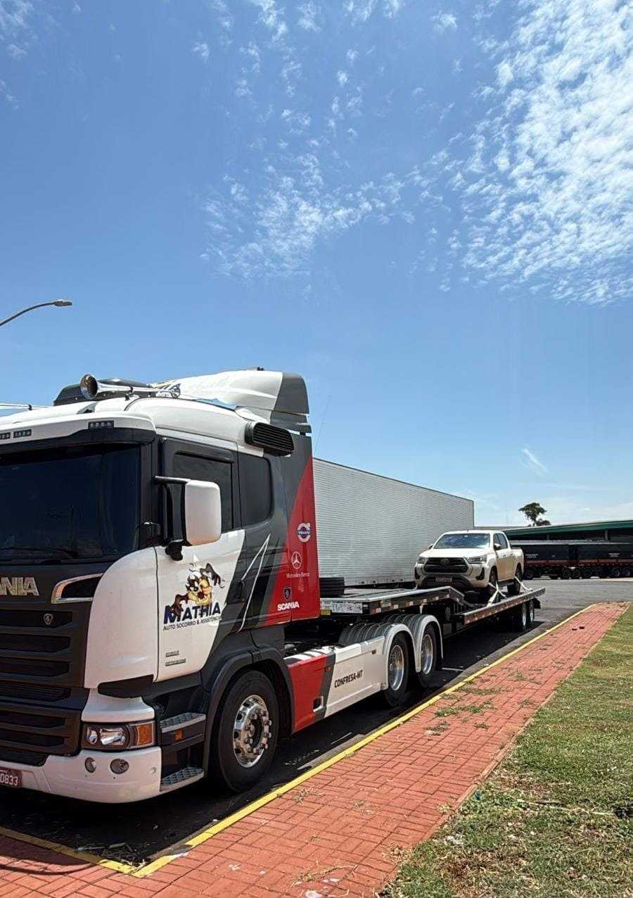 Prancha da Mathia Auto Socorro transportando uma picape, sob céu azul
